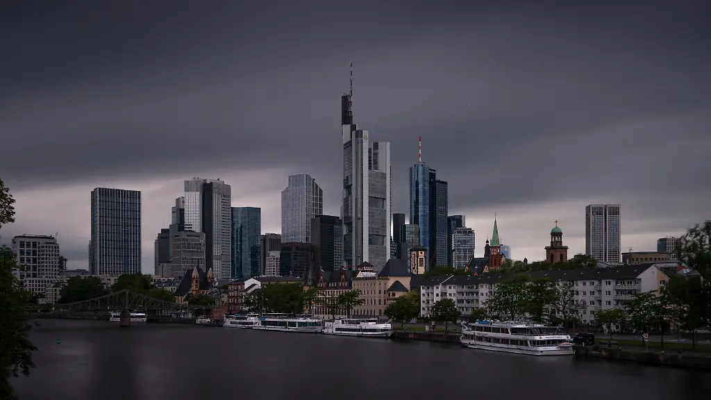 Tief-dunkle-Wolken-ziehen-am-Morgen-ueber-die-Frankfurter-Skyline-hinweg-Das-Wetter-zeigt-sich-in-diesem-Sommer-wechselhaft-Auch-in-den-kommenden-Tagen-sollen-sich-Wolken-und-Niederschlaege-mit-Sonnenschein-abwechseln-wobei-die-Temperaturen-fuer-Anfang-Juli-eher-niedrig-bleiben