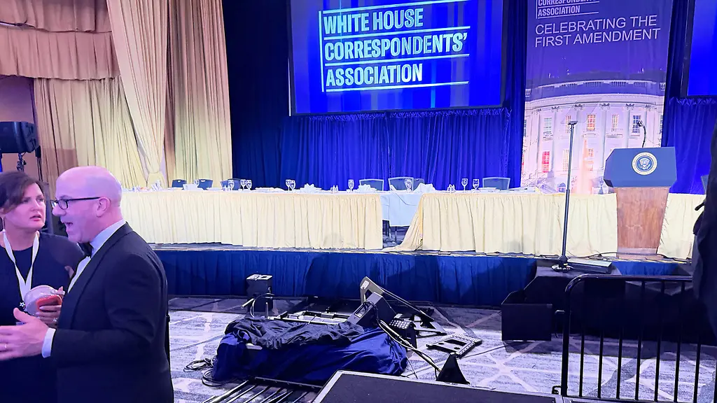 The-empty-stage-is-seen-after-President-Donald-Trump-and-other-top-leaders-were-evacuated-from-an-annual-dinner-of-White-House-correspondents-on-Saturday-night-April-25-2026-in-Washington-AP-Photo-Zeke-Miller