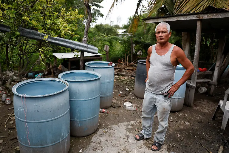 Francisco-Leyva-Gonzales-poses-for-a-picture-next-to-the-containers-he-uses-to-collect-rainwater-due-to-a-lack-of-drinking-water-supply-in-Xpujil-Campeche-state-Mexico-November-14-2025-Mexico-s-1-500-km-Mayan-Train-was-launched-to-drive-development-in-the-country-s-impoverished-south-through-infrastructure-and-tourism-but-two-years-after-its-inauguration-it-is-struggling-financially-ticket-sales-cover-only-a-fraction-of-costs-hotels-remain-largely-empty-and-communities-along-the-route-say-poverty-persists-and-promised-benefits-have-yet-to-materialize-A-Reuters-review-of-census-data-and-interviews-with-residents-along-the-line-found-that-poverty-remains-widespread-and-well-paid-jobs-scarce-despite-the-project-REUTERS-Daniel-Becerril-SEARCH-BECERRIL-MAYA-TRAIN-FOR-THIS-STORY-SEARCH-WIDER-IMAGE-FOR-ALL-STORIES