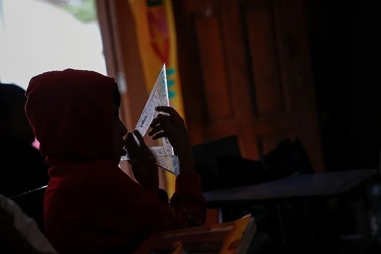 The-son-of-Mary-Sandra-Peraza-30-holds-set-squares-at-a-school-without-electricity-near-a-Maya-Train-station-with-full-electrical-service-in-Vida-y-Esperanza-Quintana-Roo-state-Mexico-November-11-2025-The-school-s-teacher-Lidia-Patricia-Chan-Us-has-spent-years-trying-to-get-power-connected-but-the-authorities-have-told-her-electricity-cannot-be-installed-until-the-land-beneath-the-school-has-formal-titles-a-red-tape-issue-common-for-rural-communal-plots-like-this-which-she-had-hoped-might-change-with-the-arrival-of-a-mega-project-that-the-government-had-vowed-would-spur-development-and-progress-At-the-beginning-when-the-project-came-along-we-were-happy-about-it-Chan-Us-said-Some-residents-sold-food-to-construction-workers-which-she-said-was-a-benefit-to-the-community-But-when-the-construction-ended-just-as-quickly-as-it-arrived-it-was-gone-REUTERS-Daniel-Becerril-SEARCH-BECERRIL-MAYA-TRAIN-FOR-THIS-STORY-SEARCH-WIDER-IMAGE-FOR-ALL-STORIES