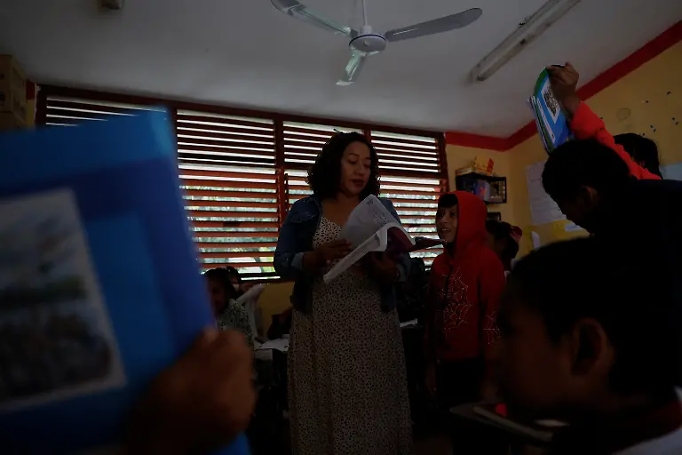 Teacher-Lidia-Patricia-Chan-Us-teaches-students-in-a-classroom-without-electricity-near-a-Maya-Train-station-with-full-electrical-service-in-Vida-y-Esperanza-Quintana-Roo-state-Mexico-November-11-2025-Chan-Us-has-spent-years-trying-to-get-power-connected-but-the-authorities-have-told-her-electricity-cannot-be-installed-until-the-land-beneath-the-school-has-formal-titles-a-red-tape-issue-common-for-rural-communal-plots-like-this-which-she-had-hoped-might-change-with-the-arrival-of-a-mega-project-that-the-government-had-vowed-would-spur-development-and-progress-At-the-beginning-when-the-project-came-along-we-were-happy-about-it-Chan-Us-said-Some-residents-sold-food-to-construction-workers-which-she-said-was-a-benefit-to-the-community-But-when-the-construction-ended-just-as-quickly-as-it-arrived-it-was-gone-REUTERS-Daniel-Becerril-SEARCH-BECERRIL-MAYA-TRAIN-FOR-THIS-STORY-SEARCH-WIDER-IMAGE-FOR-ALL-STORIES