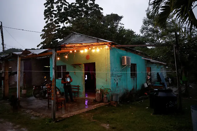 Carlos-Augusto-Gonzalez-looks-at-his-phone-outside-his-home-as-he-collects-rainwater-because-of-a-lack-of-drinking-water-supply-in-Xpujil-Campeche-state-Mexico-November-13-2025-Mexico-s-1-500-km-Mayan-Train-was-launched-to-drive-development-in-the-country-s-impoverished-south-through-infrastructure-and-tourism-but-two-years-after-its-inauguration-it-is-struggling-financially-ticket-sales-cover-only-a-fraction-of-costs-hotels-remain-largely-empty-and-communities-along-the-route-say-poverty-persists-and-promised-benefits-have-yet-to-materialize-A-Reuters-review-of-census-data-and-interviews-with-residents-along-the-line-found-that-poverty-remains-widespread-and-well-paid-jobs-scarce-despite-the-project-REUTERS-Daniel-Becerril-SEARCH-BECERRIL-MAYA-TRAIN-FOR-THIS-STORY-SEARCH-WIDER-IMAGE-FOR-ALL-STORIES