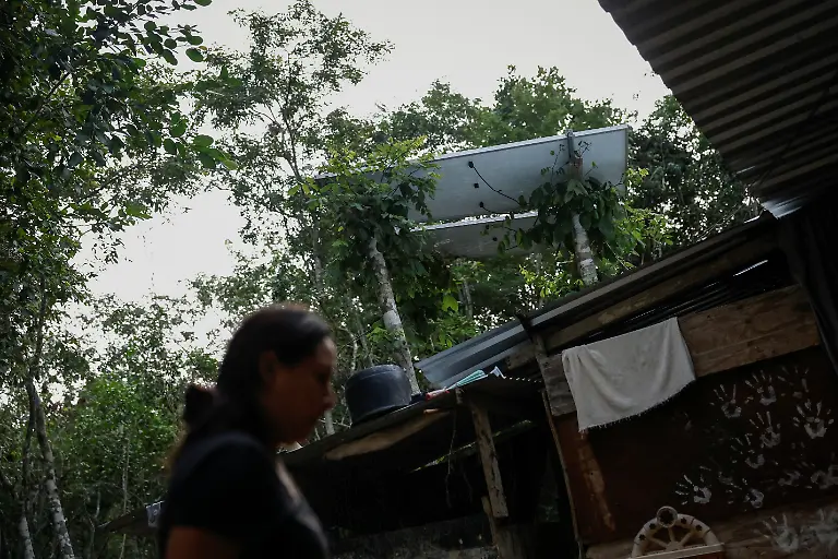 Mary-Sandra-Peraza-30-stands-at-her-family-home-where-they-lack-electricity-and-rely-on-solar-panels-and-a-generator-for-daily-tasks-near-a-Maya-Train-station-with-full-electrical-service-in-Vida-y-Esperanza-Quintana-Roo-state-Mexico-November-11-2025-Mexico-s-1-500-km-Mayan-Train-was-launched-to-drive-development-in-the-country-s-impoverished-south-through-infrastructure-and-tourism-but-two-years-after-its-inauguration-the-local-communities-near-the-line-say-they-have-seen-little-benefit-A-Reuters-review-of-census-data-and-interviews-with-dozens-of-residents-in-towns-along-the-track-found-that-poverty-remains-entrenched-and-well-paying-jobs-hard-to-find-It-s-not-like-we-re-asking-for-much-said-Peraza-There-s-no-real-benefit-for-us-REUTERS-Daniel-Becerril-SEARCH-BECERRIL-MAYA-TRAIN-FOR-THIS-STORY-SEARCH-WIDER-IMAGE-FOR-ALL-STORIES