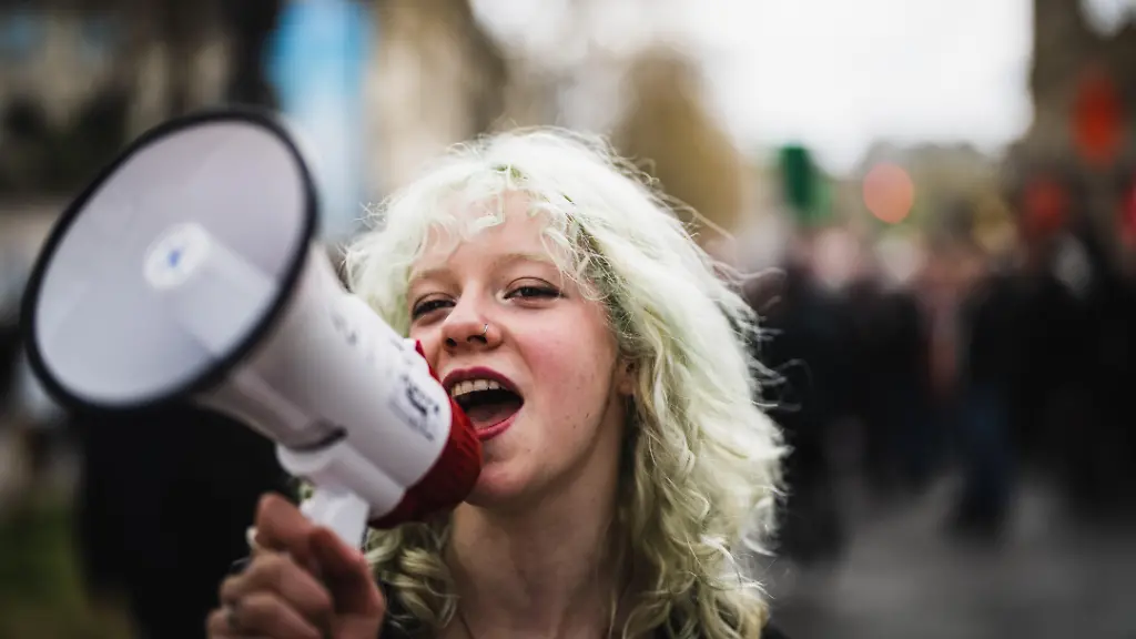 France-Paris-2023-04-06-Photograph-by-Xose-Bouzas-Hans-Lucas-Demonstration-against-the-french-government-s-pension-reform-following-a-forced-passage-without-a-vote-by-using-the-49-3-article-of-the-constitution-The-demonstrators-oppose-the-postponement-of-the-legal-age-to-64-years-A-young-smiling-female-student-protester-shouts-slogans-against-the-pension-reform-with-a-megaphone-France-Paris-2023-04-06-Photographie-par-Xose-Bouzas-Hans-Lucas-Manifestation-contre-la-reforme-des-retraites-du-gouvernement-suite-a-un-passage-en-force-sans-vote-en-recourant-a-l-article-49-3-de-la-constitution-Les-manifestants-s-opposent-au-report-de-l-age-legal-a-64-ans-Une-jeune-femme-manifestante-etudiante-souriante-crie-des-slogans-contre-la-reforme-des-retraites-a-l-aide-d-un-megaphone
