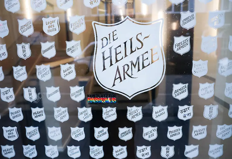 Das-Logo-der-Heilsarmee-ist-in-vielen-verschiedenen-Sprachen-an-einer-Tuer-des-Gebaeudes-der-Heilsarmee-Korps-Hamburg-mit-der-Tages-und-Begegnungsstaette-Heimathafen-Heilsarmee-in-der-Talstrasse-an-der-Reeperbahn-zu-sehen