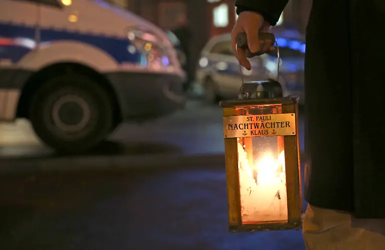 Ein-Touristenfuehrer-haelt-am-13-01-2014-in-Hamburg-auf-der-Reeperbahn-vor-der-Davidwache-eine-Laterne-in-der-Hand-Touristen-Fuehrer-und-Ladenmitarbeiter-auf-der-Reeperbahn-haben-die-Folgen-der-Krawalle-und-der-Einrichtung-von-Gefahrengebieten-durch-die-Polizei-gespuert-Foto-Axel-Heimken-dpa-zu-dpa-Randale-Proteste-Gefahrengebiete-Arbeiten-auf-der-Reeperbahn-vom-14-01