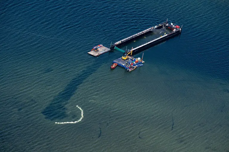 Der-in-der-Ostsee-gestrandete-Buckelwal-ist-in-dem-fuer-seinen-Transport-vorgesehenen-Lastkahn-angekommen-Das-Tier-bewegte-sich-durch-eine-zuvor-ausgebaggerte-Rinne-in-die-sogenannte-Barge-nachdem-Helfer-ihn-zuvor-mit-Gurten-in-diese-Richtung-gezogen-hatten-Der-vor-ueber-drei-Wochen-bei-Wismar-gestrandete-Buckelwal-soll-nun-mit-dem-Schiff-in-die-Nordsee-gebracht-werden-Eine-private-Initiative-hatte-seit-Tagen-versucht-den-Wal-zu-retten