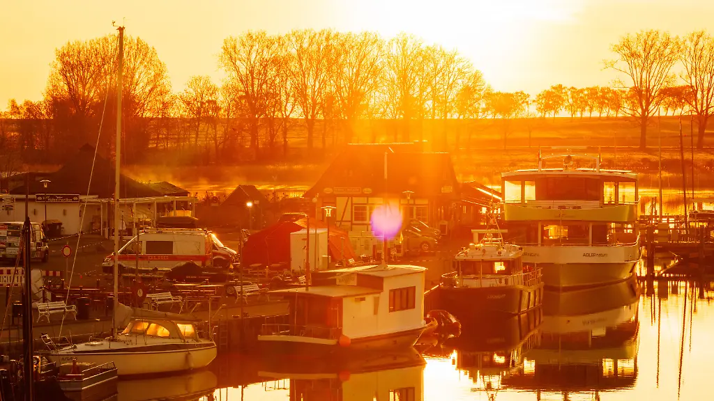 Die-Sonne-geht-hinter-dem-Kleinen-Hafen-auf-der-Insel-Poel-auf-Von-hier-starten-die-Helfer-und-Walexperten-zu-ihren-Einsaetzen-zur-Versorgung-des-gestrandeten-Buckelwals-Der-vor-ueber-drei-Wochen-bei-Wismar-gestrandete-Buckelwal-liegt-weiterhin-im-Flachwasser-fest-Eine-private-Initiative-versucht-seit-Tagen-den-Wal-zu-retten