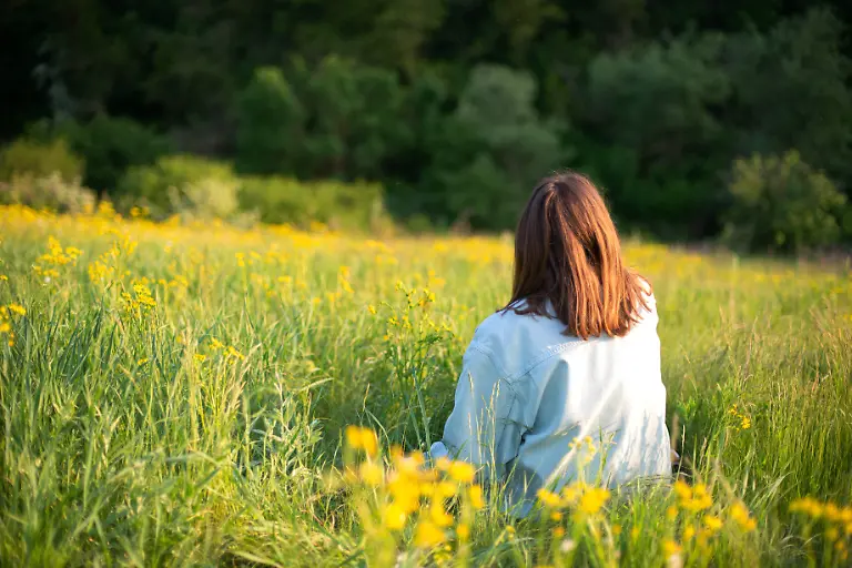 Portrait-of-confident-young-woman-sitting-in-field-Bristol-England-United-Kingdom-CR-INCH21092804-843113-01-model-released-Symbolfoto