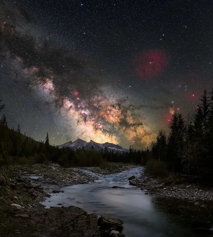 Taking-advantage-of-the-April-new-moon-I-set-out-to-capture-my-first-Milky-Way-image-of-2025-With-promising-conditions-forecast-across-southern-Poland-I-returned-to-the-Tatra-Mountains-a-region-I-often-revisit-with-my-camera-this-time-exploring-the-Białka-Gorge-in-Jurgow-a-location-I-had-not-photographed-before-From-this-vantage-point-the-Milky-Way-rises-above-the-Tatras-which-in-early-spring-still-carry-the-lingering-traces-of-winter-What-drew-me-most-to-this-scene-was-the-contrast-between-the-dark-rugged-landscape-and-the-richness-of-the-sky-The-galactic-core-emerges-just-above-the-mountain-horizon-accompanied-by-the-subtle-colors-of-the-dust-and-nebulae-within-the-Rho-Ophiuchi-region-In-the-foreground-the-river-creates-a-natural-leading-line-guiding-the-eye-from-the-earth-toward-the-mountains-and-into-the-night-sky-visually-connecting-the-terrestrial-and-the-cosmic-Beyond-the-final-image-astrophotography-is-equally-about-the-experience-in-the-field-often-shared-with-others-who-are-drawn-to-the-same-conditions-and-moments-united-by-a-common-appreciation-for-the-night-sky