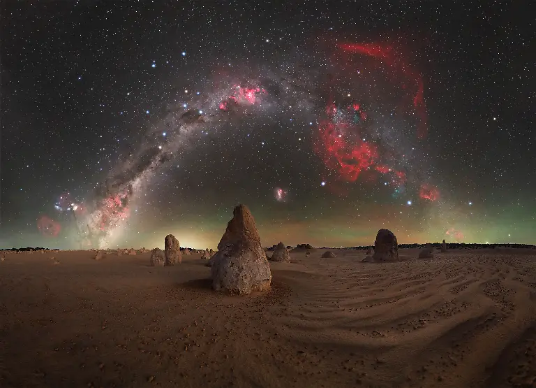 There-s-something-uniquely-powerful-about-a-calm-windless-night-in-the-Pinnacles-Desert-a-place-that-never-fails-to-remind-me-how-fortunate-we-are-to-have-such-pristine-dark-skies-so-close-to-home-just-a-short-drive-away-As-the-sun-sets-beyond-the-Indian-Ocean-a-profound-stillness-settles-over-Nambung-transforming-the-landscape-into-an-almost-otherworldly-scene-and-drawing-me-back-here-time-and-time-again-In-this-composition-the-main-limestone-pillar-aligns-almost-perfectly-with-the-South-Celestial-Pole-anchoring-the-image-beneath-the-rotating-sky-To-the-right-the-faint-but-unmistakable-red-glow-of-the-Gum-Nebula-a-vast-supernova-remnant-adds-depth-and-scale-to-the-scene-Western-Australia-offers-some-of-the-finest-night-skies-in-the-world-yet-it-s-easy-to-take-them-for-granted-Nights-like-this-serve-as-a-reminder-of-just-how-special-these-quiet-remote-corners-of-the-Wheatbelt-truly-are