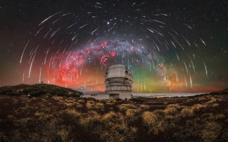 This-winter-Milky-Way-panorama-captures-a-sky-filled-with-Geminid-meteors-above-the-Gran-Telescopio-Canarias-the-largest-optical-telescope-in-the-world-My-first-trip-to-La-Palma-was-an-intense-and-unpredictable-experience-from-storms-and-summit-snowfall-to-strong-winds-rain-and-brief-windows-of-clear-skies-For-the-first-three-nights-we-were-confined-to-the-southern-part-of-the-island-as-the-road-to-the-Roque-de-los-Muchachos-Observatory-remained-closed-forcing-us-to-search-for-clear-conditions-elsewhere-Reaching-the-summit-seemed-increasingly-unlikely-until-the-fourth-day-when-the-road-finally-reopened-We-immediately-made-our-way-up-filled-with-anticipation-After-scouting-compositions-and-preparing-for-the-night-clouds-once-again-moved-in-putting-everything-at-risk-Rather-than-giving-up-we-waited-constantly-checking-the-sky-for-any-sign-of-improvement-Around-midnight-the-first-stars-began-to-appear-and-we-quickly-headed-to-the-Gran-Telescopio-Canarias-Above-us-the-sky-opened-into-a-field-of-stars-while-a-layer-of-clouds-remained-below-creating-a-striking-contrast-with-the-illuminated-structure-of-the-telescope-Although-the-dome-could-not-be-opened-due-to-humidity-the-experience-of-witnessing-such-dark-skies-for-the-first-time-was-remarkable-with-the-Milky-Way-appearing-almost-three-dimensional-This-was-also-my-first-successful-capture-of-the-Gum-Nebula-adding-a-unique-element-to-the-composition-The-final-image-is-the-result-of-an-extensive-post-processing-workflow-combining-meteor-data-registered-using-Auriga-RegiStar-from-six-cameras-over-five-nights-on-La-Palma-All-RGB-frames-were-captured-using-the-Capture-the-Night-Astro-filter-by-Capture-the-Atlas-The-final-resolution-reaches-approximately-400-megapixels-This-image-reflects-not-only-the-complexity-of-the-process-but-also-the-experience-behind-it-Each-time-I-revisit-it-it-brings-me-back-to-that-unforgettable-time-on-La-Palma