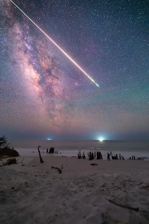 This-single-exposure-image-became-a-reminder-to-always-expect-the-unexpected-in-astrophotography-I-had-not-even-planned-to-visit-this-beach-as-the-forecast-called-for-clouds-and-rain-throughout-the-night-The-capture-was-part-of-a-larger-day-to-night-time-lapse-that-I-began-shooting-at-golden-hour-working-through-biting-insects-and-the-intense-tropical-humidity-of-Florida-After-setting-up-the-sequence-I-left-the-camera-running-and-returned-to-my-vehicle-Several-hours-later-shortly-after-midnight-I-noticed-the-ground-around-me-suddenly-illuminated-by-a-green-glow-prompting-me-to-look-up-What-followed-was-the-largest-meteor-I-have-ever-witnessed-It-moved-slowly-across-the-Milky-Way-for-nearly-five-seconds-and-the-glowing-trail-left-behind-by-the-fireball-remained-visible-for-almost-fifteen-minutes-It-was-one-of-the-most-memorable-moments-I-have-experienced-in-astrophotography-completely-unplanned-and-impossible-to-anticipate