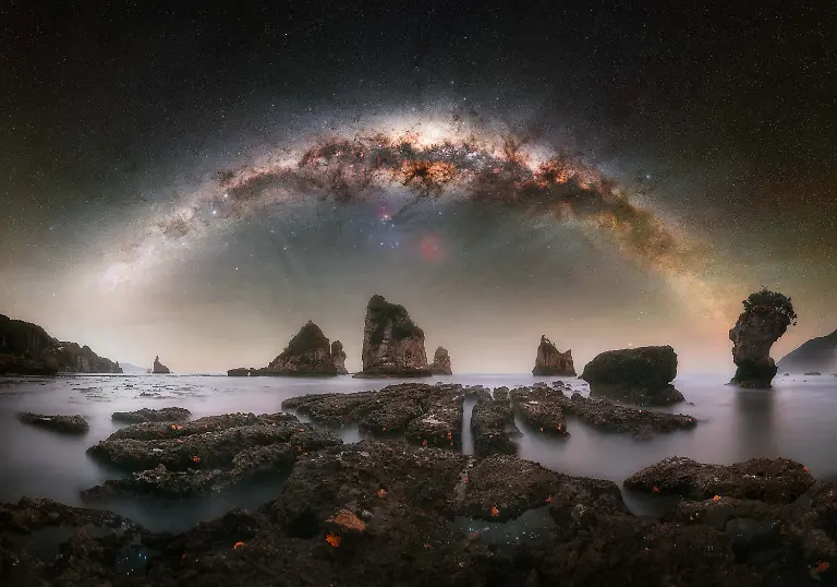 Capturing-a-setting-Milky-Way-core-from-this-beach-had-been-on-my-list-for-a-long-time-with-the-starfish-covered-reef-offering-a-distinctive-and-compelling-foreground-It-s-a-notoriously-difficult-scene-to-photograph-as-access-to-the-reef-is-only-possible-during-the-lowest-tides-while-the-sky-must-also-cooperate-with-favorable-moon-and-cloud-conditions-During-my-short-visit-everything-unexpectedly-aligned-At-first-the-conditions-seemed-uncertain-due-to-strong-winds-but-I-decided-to-attempt-the-shot-with-some-company-for-safety-After-assessing-the-reef-I-carefully-made-my-way-onto-it-while-others-kept-watch-to-ensure-I-remained-safe-The-terrain-is-hazardous-with-gaps-between-the-rocks-posing-a-real-risk-and-the-rapidly-rising-tide-added-constant-pressure-throughout-the-shoot-Despite-these-challenges-I-was-able-to-capture-the-necessary-frames-returning-to-shore-just-in-time-Due-to-the-changing-tide-the-upper-rows-of-the-sky-panorama-were-photographed-from-the-beach-while-the-lowest-row-was-captured-from-the-reef-to-maintain-proper-alignment-and-perspective-in-the-final-composition