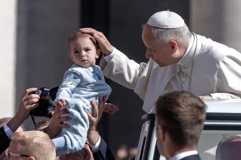 Pope-Leo-XIV-greets-a-child-as-he-arrives-for-his-weekly-general-audience-in-St-Peter-s-square-at-the-Vatican