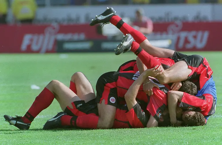 ARCHIV-Ein-Knaeuel-Frankfurter-Spieler-jubelt-nach-dem-5-1-Sieg-der-Eintracht-gegen-den-1-FC-Kaiserslautern-am-29-05-1999-im-Frankfurter-Waldstadion-Die-Frankfurter-schafften-den-Klassenerhalt-durch-eine-gleichzeitige-Niederlage-des-1-FC-Nuernberg-gegen-den-SC-Freiburg-Durch-den-vierten-Frankfurter-Sieg-in-Serie-wurde-das-Fussball-Wunder-wahr-gemacht-Foto-Katja-Lenz-dpa-zu-dpa-Meldung-Joerg-Berger-und-die-Titanic-Frankfurts-wundersame-Rettung-1999-vom-22-05
