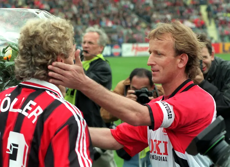ARCHIV-Leverkusens-Stuermer-Rudi-Voeller-l-nimmt-vor-seinem-letztes-Bundesligaspiel-von-Kaiserslauterns-Kapitaen-Andreas-Brehme-einen-Blumenstrauss-und-die-Gratulation-entgegen-Archivfoto-vom-18-05-1996-An-diesem-Tag-stieg-das-Bundesliga-Gruendungsmitglied-1-FC-Kaiserslautern-nach-einem-1-1-im-Abstiegs-Endspiel-bei-Bayer-04-Leverkusen-erstmals-nach-33-Jahren-aus-der-Eliteliga-ab-Foto-Gero-Breloer-dpa-zu-dpa-Meldung-Brehme-Fjoertoft-Salihovic-Abstiegsdramen-am-letzten-Spieltag-vom-13-05