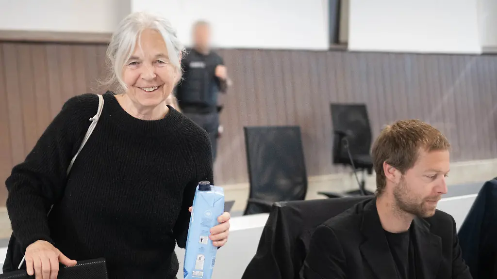 Die-Angeklagte-Daniela-Klette-steht-zu-Beginn-des-Verhandlungstages-im-provisorischen-Gerichtssaal-des-Landgerichts-Verden-in-Verden-Eitze-neben-ihrem-Anwalt-Lukas-Theune-Im-Prozess-gegen-die-fruehere-RAF-Terroristin-Daniela-Klette-wegen-schweren-Raubes-werden-Plaedoyers-der-Verteidigung-erwartet