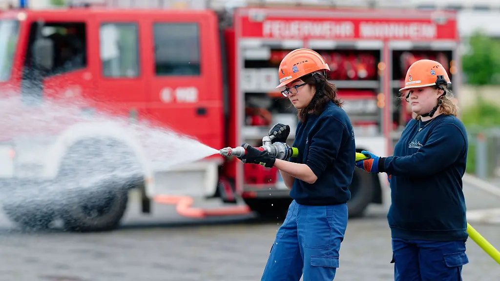 Ilias-links-und-Annabella-Mitglieder-der-Jugendfeuerwehr-in-Mannheim-halten-bei-einer-Uebung-einen-Feuerwehrschlauch-in-den-Haenden