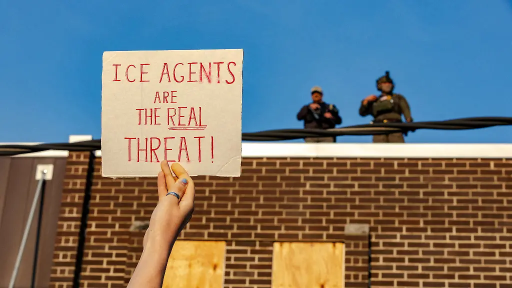 FILE-PHOTO-A-protester-holds-up-a-sign-as-federal-agents-stand-guard-on-top-of-the-Broadview-ICE-detention-facility-after-U-S-President-Donald-Trump-ordered-increased-federal-law-enforcement-presence-to-assist-in-crime-prevention-in-Broadview-Illinois-U-S-September-19-2025