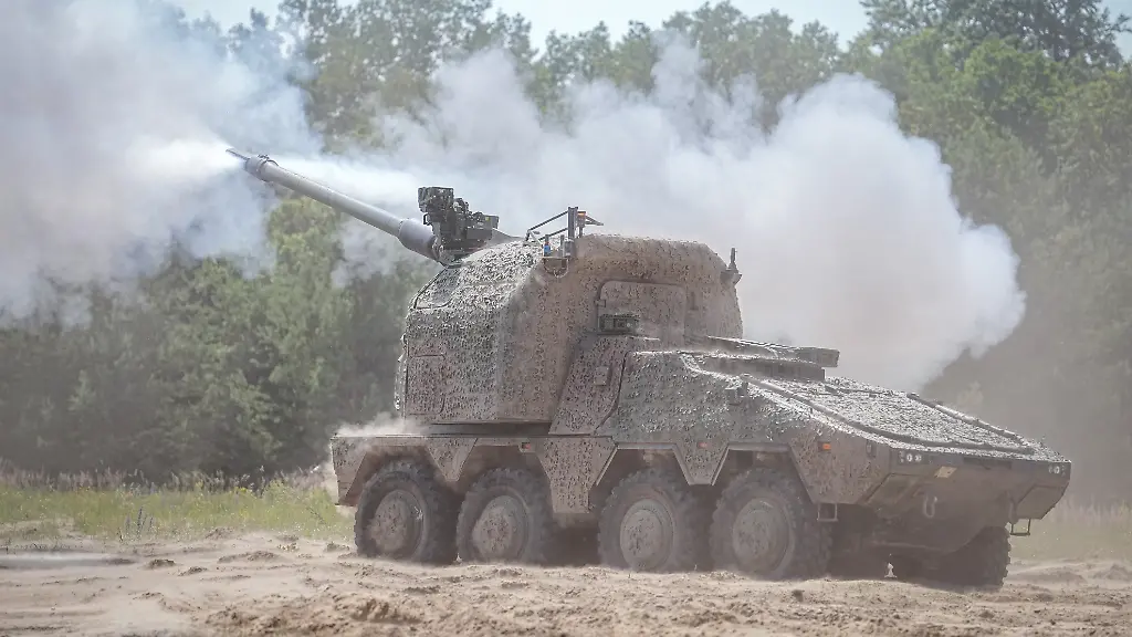 Eine-neue-Radhaubitze-RCH-155-des-Panzerherstellers-KNDS-feuert-bei-einer-Praesentation-auf-dem-Truppenuebungsplatz-Altengrabow-ein-Geschoss-ab-KNDS-nutzt-hier-die-Plattform-des-Radpanzers-Boxer-als-Waffentraeger-fuer-ein-automatisiertes-und-fernbedienbares-Artilleriegeschuetz-Mit-der-vollautomatisiert-und-aus-laufender-Fahrt-schiessenden-Radhaubitze-verspricht-der-Panzerbauer-KNDS-der-Bundeswehr-und-den-Streitkraeften-von-Partnerstaaten-einen-Vorteil-auf-dem-Gefechtsfeld-Zudem-sollen-zwei-Soldaten-als-Besatzung-ausreichen-wo-bisher-in-der-auf-Ketten-rollenden-Panzerhaubitze-2000-noch-fuenf-Mann-als-Fahrer-und-Bediener-noetig-sind