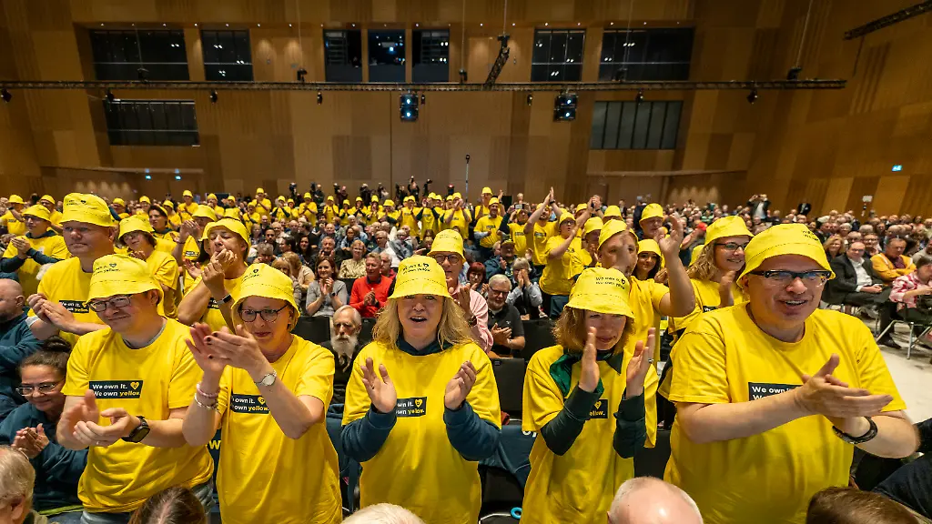 Aktionaere-bekunden-auf-der-Hauptversammlung-der-Commerzbank-im-RheinMain-CongressCenter-RMCC-mit-gelben-T-Shirts-und-Kappen-ihre-Abneigung-gegen-einen-moeglichen-Uebernahmeversuch-durch-die-Unicredit-Im-zweiten-Jahr-in-Folge-ist-eine-drohende-Uebernahme-durch-die-Unicredit-bestimmendes-Thema-der-Commerzbank-Hauptversammlung