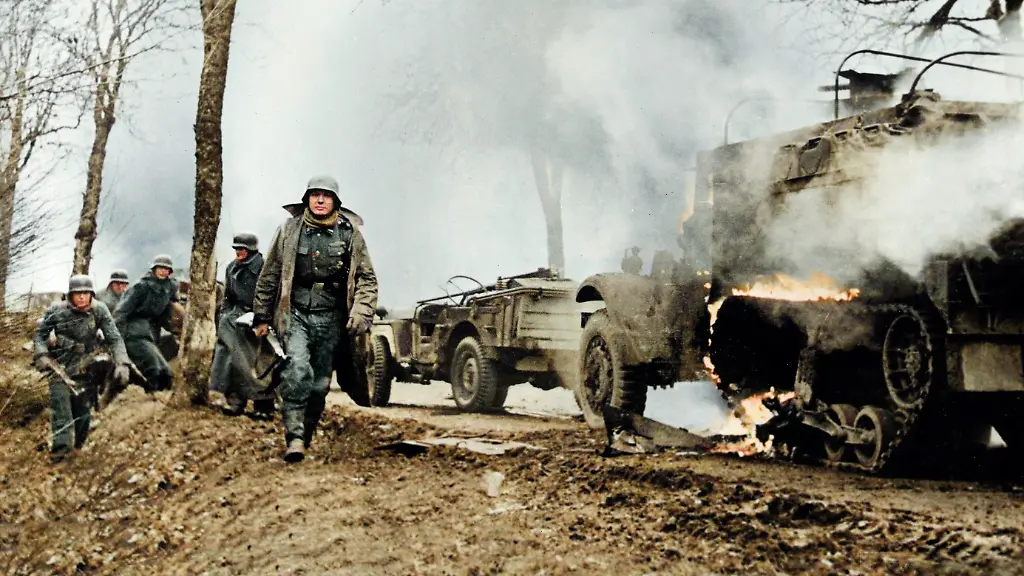 World-War-II-Battle-of-the-Bulge-Ardennes-Offensive-last-major-German-offensive-campaign-on-the-Western-Front-December-1944-January-1945-German-infantrymen-pass-burning-captured-American-vehicles-somewhere-on-front-during-German-drive-into-lines-photographed-by-a-German-army-camerman-whose-films-were-later-captured-by-American-forces-Photo-December-17-1945