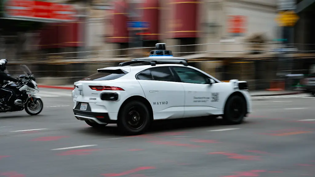 A-police-officer-riding-a-motorcycle-follows-a-Waymo-driverless-car-as-it-drives-through-downtown-Los-Angeles-California-U-S-May-1-2026