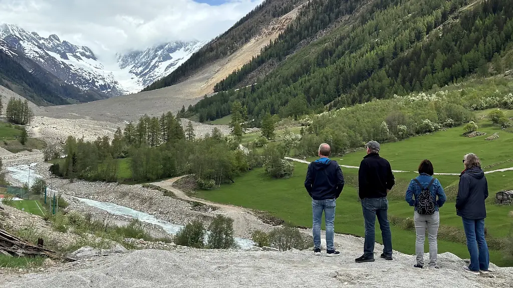 PRODUKTION-05-05-2026-Schweiz-Blatten-Besucher-schauen-an-der-abgesperrten-Strasse-auf-den-Schuttberg-wo-einst-das-Dorf-Blatten-mit-300-Einwohnern-lag-Von-dem-Dorf-ist-nur-wenig-uebrig-geblieben-zunaechst-unversehrte-Haeuser-sind-im-See-versunken-der-durch-die-gestaute-Lonza-hinter-dem-Schuttberg-entstand