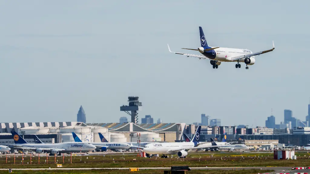 Eine-Maschine-der-Lufthansa-ist-im-Landeanflug-auf-den-Flughafen-Frankfurt-Im-Hintergrund-sind-die-Kerosinlager-und-Maschinen-auf-ihrer-Parkposition-zu-sehen-Mehrere-Airlines-bereiteten-sich-nach-Medienberichten-auf-einen-moeglichen-Kersosinmangel-in-Folge-des-Iran-Krieges-vor
