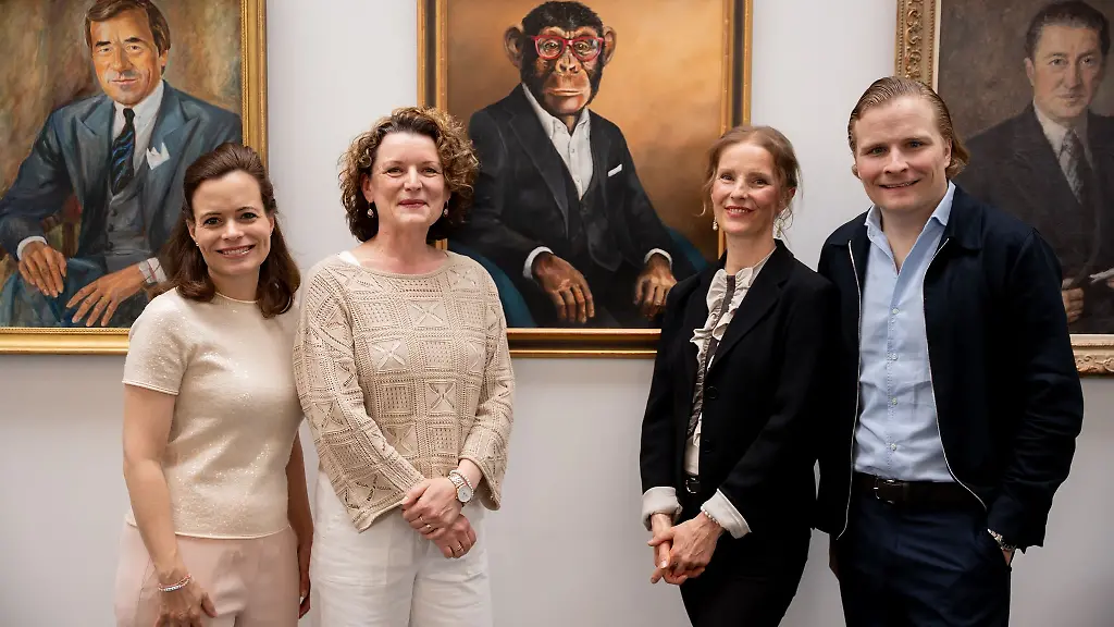 Maskottchen-Charly-haengt-nun-in-der-Ahnengalerie-der-Familie-Grupp-beim-Bekleidungsunternehmen-Trigema-Bonita-Grupp-von-links-Malerin-Hanna-Bastian-Bildeinrahmerin-Sylvia-Reh-und-Wolfgang-Grupp-junior-vor-dem-Portraet-in-Oel-von-Charly