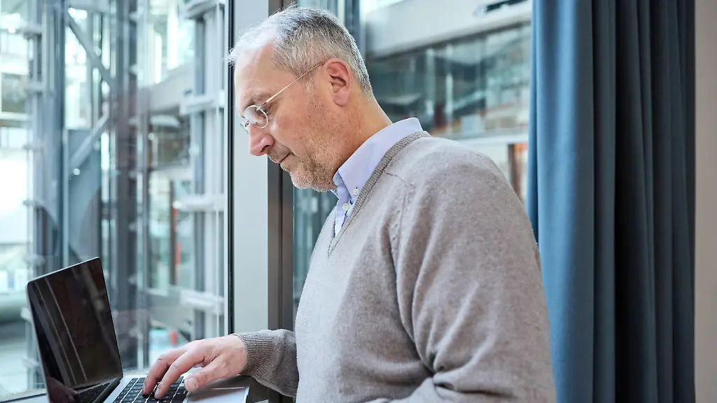 Ein-aelterer-Mann-arbeitet-konzentriert-an-einem-Laptop-in-einer-modernen-Bueroumgebung
