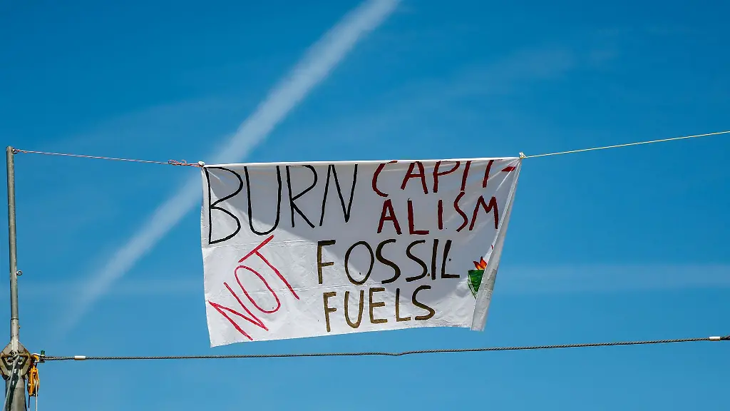 Ein-Banner-mit-der-Aufschrift-Burn-Capitalism-not-Fossil-Fuels-ist-an-einem-Seil-im-Klimacamp-befestigt