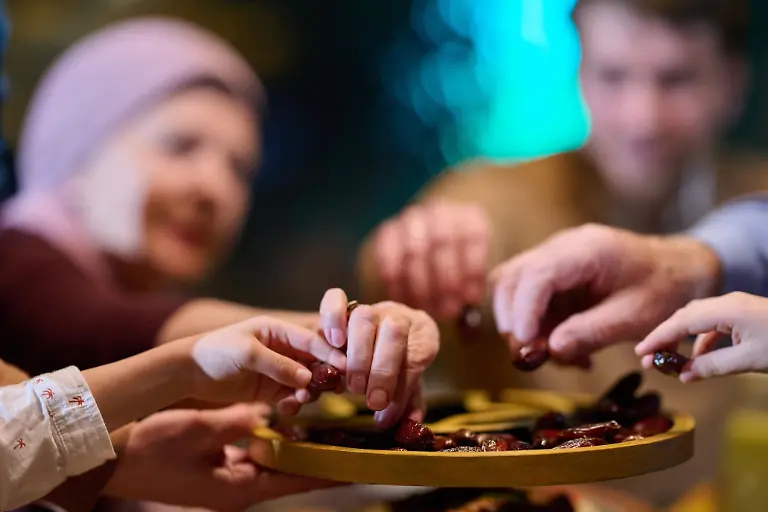 Eine-muslimische-Familie-teilt-iftar-in-einem-Restaurant-Sie-sammeln-sich-um-ein-Tablett-von-Terminen-und-bereiten-sich-vor-waehrend-der-Ramadan-Feiern-zusammenzubrechen