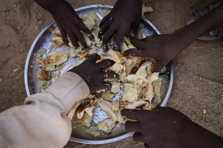 Sudanese-refugee-children-from-Al-Fashir-displaced-by-ongoing-conflict-in-Sudan-between-the-paramilitary-Rapid-Support-Forces-RSF-and-the-Sudanese-army-share-a-free-meal-of-porridge-and-bread-from-a-single-plate-provided-by-the-Civilian-Network-for-Justice-with-support-from-the-Strategic-Initiative-for-Women-in-the-Horn-of-Africa-SIHA-Network-at-the-Tine-transit-camp-in-eastern-Chad-November-23-2025-REUTERS-Amr-Abdallah-Dalsh-SEARCH-ABDALLAH-DALSH-SUDAN-SURVIVORS-FOR-THIS-STORY-SEARCH-WIDER-IMAGE-FOR-ALL-STORIES