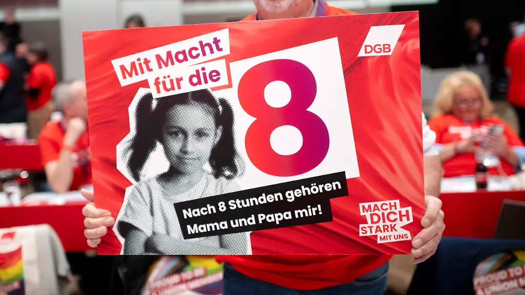 DEU-Deutschland-Germany-Berlin-12-05-2026-Delegierter-mit-Schild-Die-Macht-fuer-die-Acht-8-Haende-Weg-vom-8-Stunden-Tag-als-Protest-waehrend-der-Rede-vom-Bundeskanzler-auf-dem-23-Ordentlichen-Bundeskongress-Deutscher-Gewerkschaftsbund-DGB-unter-dem-Motto-Staerker-mit-uns-in-Berlin-Germany-en-Delegate-with-Sign-Power-to-the-Eight-Hands-Off-the-8-Hour-Day-in-protest-during-the-Federal-Chancellor-s-speech-at-the-23rd-Ordinary-Federal-Congress-of-the-German-Trade-Union-Confederation-DGB-Deutscher-Gewerkschaftsbund-held-under-the-motto-Stronger-with-Us-Staerker-mit-uns-in-Berlin-Germany