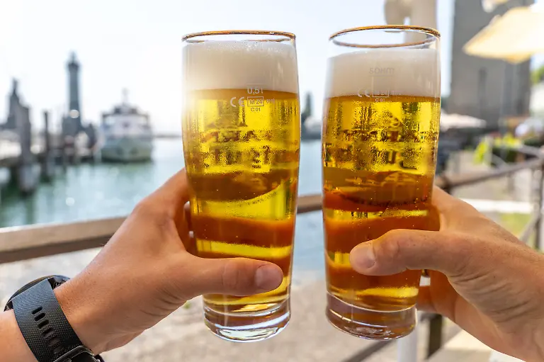Prost-am-Wasser-im-Urlaub-zwei-kuehle-Bierglaeser-im-Sommerlicht