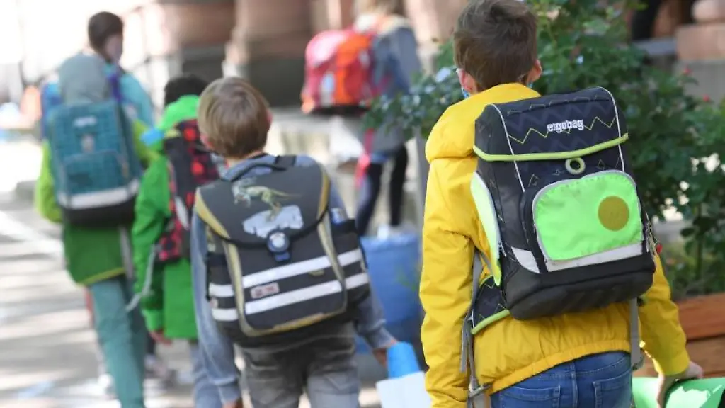 Schuelerinnen-und-Schueler-einer-vierten-Klasse-gehen-auf-dem-Schulhof-ins-Schulgebaeude