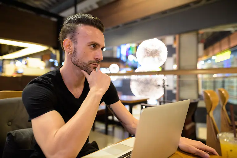 Portrait-of-handsome-man-sitting-indoors-at-coffee-shop-Modellfreigabe-vorhanden