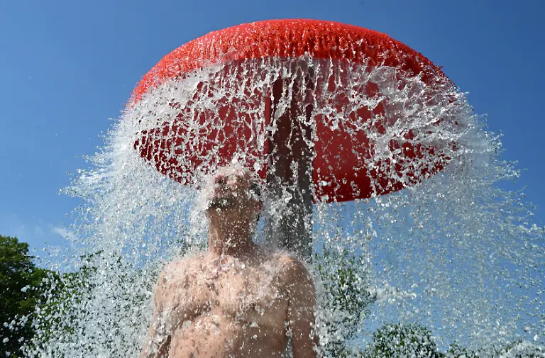 Ein-Besucher-des-Freibads-Moehringen-steht-bei-sommerlichen-Temperaturen-unter-einer-kuehlenden-Wasserdusche