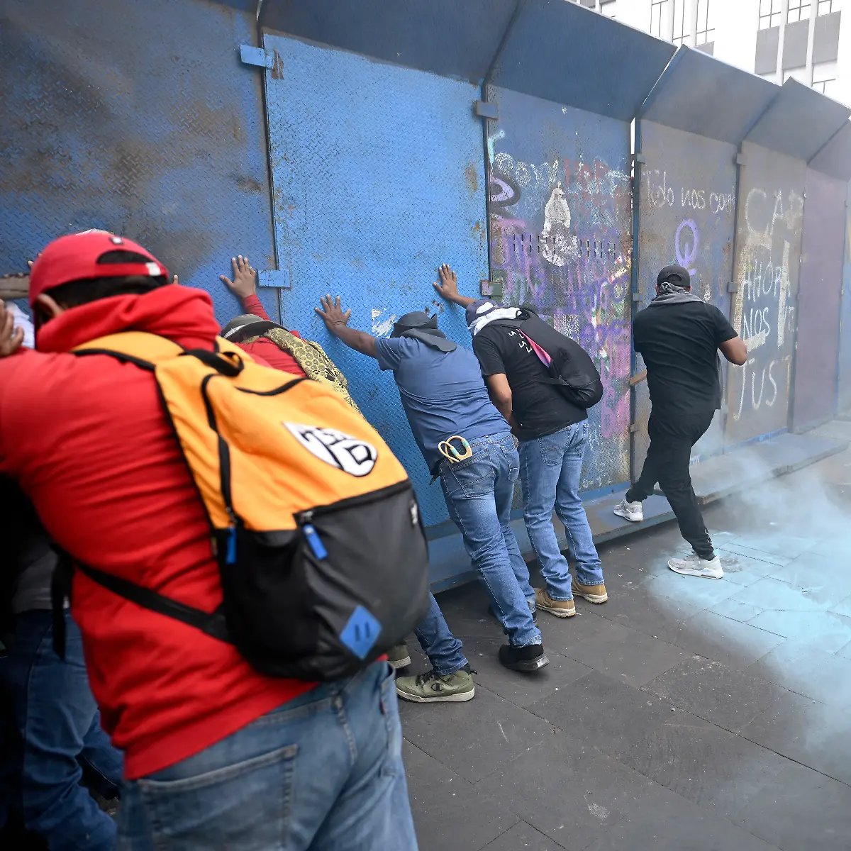 Teachers-push-against-a-barricade-blocking-access-to-the-Zocalo-as-blue-smoke-from-a-fire-extinguisher-discharged-by-police-rises-from-the-other-side-during-a-demonstration-ahead-of-the-FIFA-World-Cup-2026-in-Mexico-City-on-June-1-2026