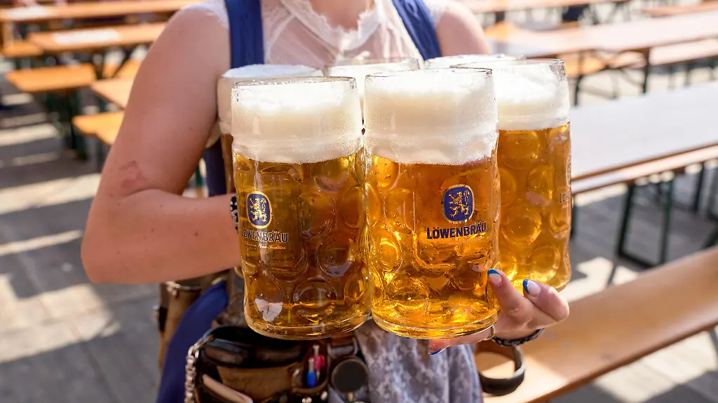 Masskruege-mit-Loewenbraeu-Bier-gehalten-von-einer-Bedienung-auf-dem-Oktoberfest-in-Muenchen