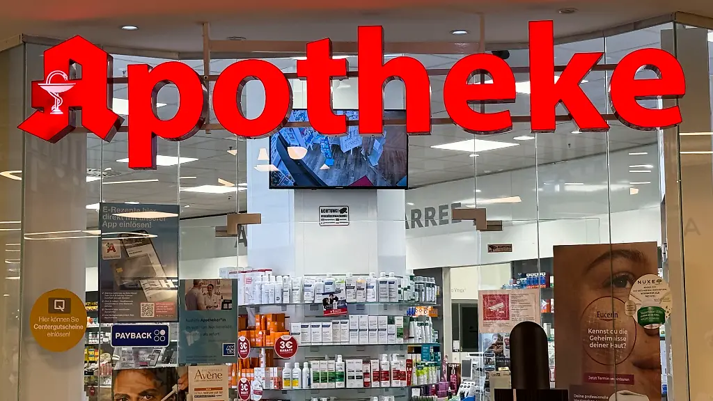 SYMB-APOTHEKE-Eingangsbereich-einer-Apotheke-mit-dem-Logo-Leuchtbuchstaben-Schriftzug-Apotkeke-in-Hamburg-Rote-A-ist-das-geschuetzte-Erkennungszeichen-fuer-oeffentliche-Apotheken-in-Deutschland-Apotheke-ist-ein-Ort-an-dem-Arzneimittel-und-Medizinprodukte-abgegeben-geprueft-und-hergestellt-werden