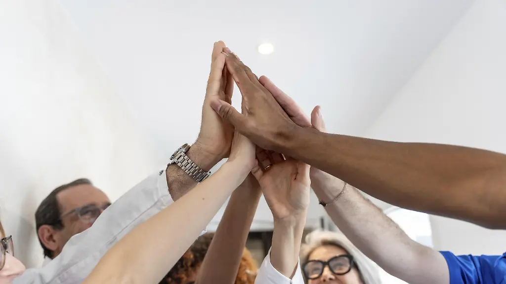 Angehoerige-der-Gesundheitsberufe-mit-unterschiedlichem-Hintergrund-feiern-Erfolg-und-Teamwork-und-heben-begeistert-ihre-Haende-in-einem-High-Five-als-Symbol-fuer-Einheit-und-Leistung-in-der-Medizin-Modellfreigabe-vorhanden