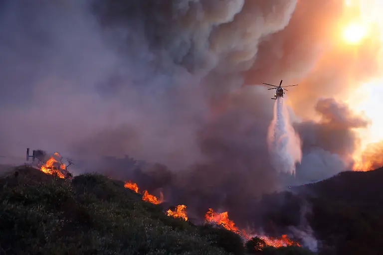 FILE-Water-is-dropped-by-helicopter-on-the-advancing-Palisades-Fire-in-the-Pacific-Palisades-neighborhood-of-Los-Angeles-Jan-7-2025