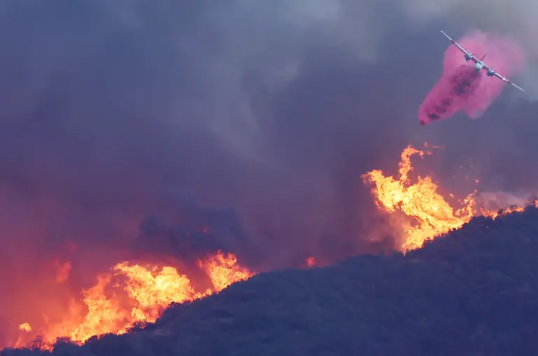PACIFIC-PALISADES-CALIFORNIA-JANUARY-07-A-firefighting-aircraft-drops-the-fire-retardant-Phos-Chek-as-the-Palisades-Fire-burns-amid-a-powerful-windstorm-on-January-7-2025-in-Pacific-Palisades-California-The-fast-moving-wildfire-is-threatening-homes-in-the-coastal-neighborhood-amid-intense-Santa-Ana-Winds-and-dry-conditions-in-Southern-California