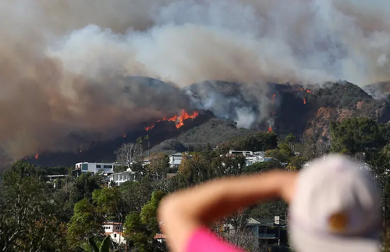 PACIFIC-PALISADES-CALIFORNIA-JANUARY-07-A-person-watches-as-the-Palisades-Fire-burns-namid-a-powerful-windstorm-on-January-7-2025-in-Pacific-Palisades-California-The-fast-moving-wildfire-is-threatening-homes-in-the-coastal-neighborhood-amid-intense-Santa-Ana-Winds-and-dry-conditions-in-Southern-California