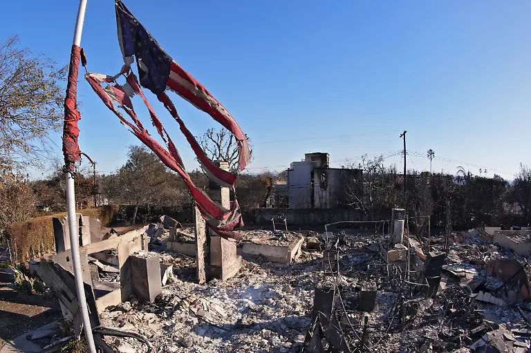 An-American-flag-is-seen-tattered-as-it-flies-above-a-burned-down-home-after-the-Palisades-Fire-Sunday-Jan-12-2025-in-the-Pacific-Palisades-section-of-Los-Angeles-AP-Photo-Mark-J