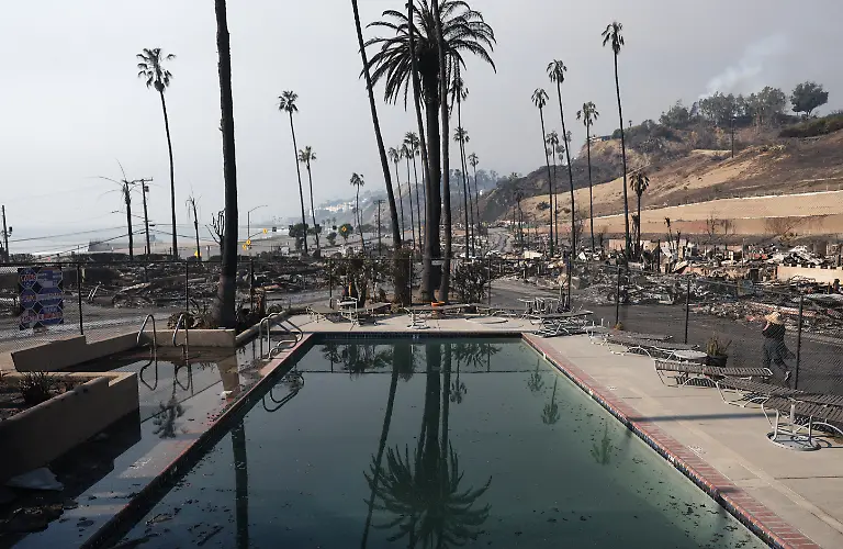 PACIFIC-PALISADES-CALIFORNIA-JANUARY-09-A-person-walks-through-a-community-destroyed-in-the-Palisades-Fire-on-January-09-2025-in-Pacific-Palisades-California-Multiple-wildfires-fueled-by-intense-Santa-Ana-Winds-are-burning-across-Los-Angeles-County-At-least-five-people-have-been-killed-and-over-25-000-acres-have-burned-Over-2-000-structures-have-also-burned-and-almost-180-000-people-are-under-orders-to-evacuate
