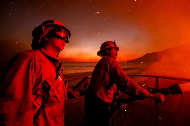 Firefighters-work-from-a-deck-as-the-Palisades-Fire-burns-a-beachfront-property-Wednesday-Jan-8-2025-in-Malibu-Calif